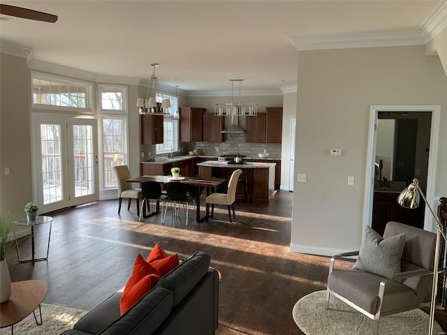 living room featuring dark hardwood / wood-style floors, sink, ornamental molding, and ceiling fan with notable chandelier