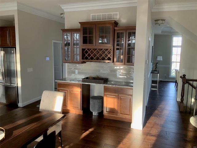 bar with light stone countertops, dark hardwood / wood-style flooring, stainless steel fridge, decorative backsplash, and ornamental molding