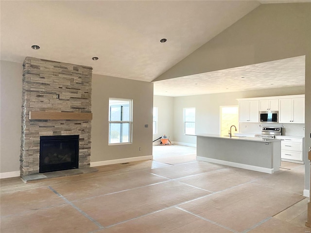 unfurnished living room featuring sink, a fireplace, and high vaulted ceiling