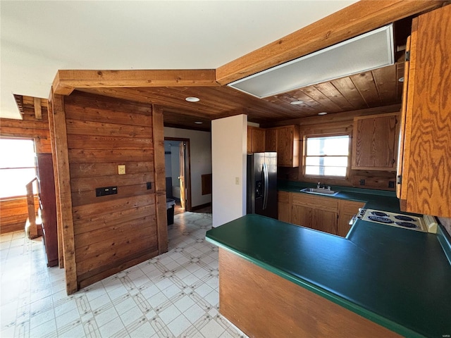 kitchen featuring a sink, dark countertops, stainless steel fridge, a peninsula, and light floors