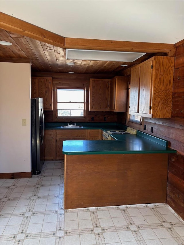 kitchen with a peninsula, dark countertops, light floors, and freestanding refrigerator