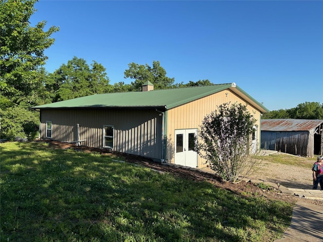 view of side of home with a lawn, a chimney, and metal roof