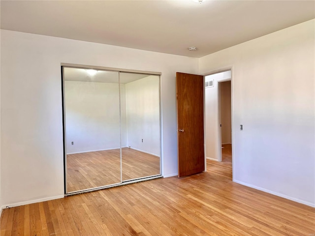 unfurnished bedroom with light wood-type flooring and a closet