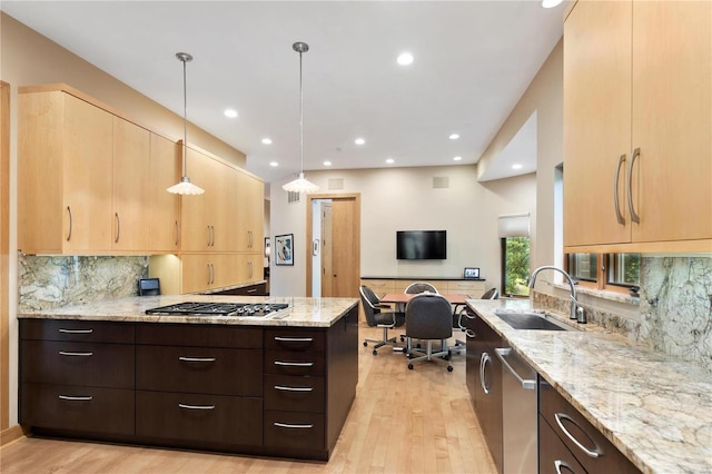 kitchen with light stone countertops, pendant lighting, stainless steel appliances, and sink