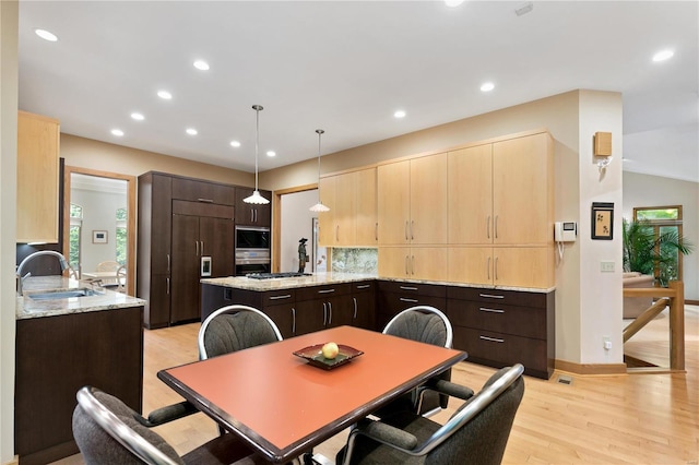 kitchen featuring sink, built in appliances, decorative light fixtures, light hardwood / wood-style flooring, and a kitchen island