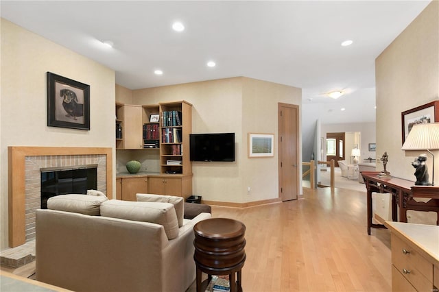 living room with a fireplace and light wood-type flooring