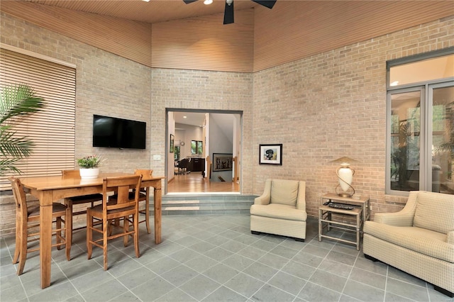 living room featuring ceiling fan, wooden ceiling, tile patterned flooring, high vaulted ceiling, and brick wall