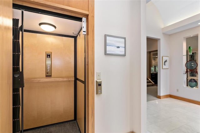 corridor with elevator and vaulted ceiling