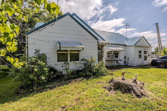 back of house with a standing seam roof, metal roof, and a lawn