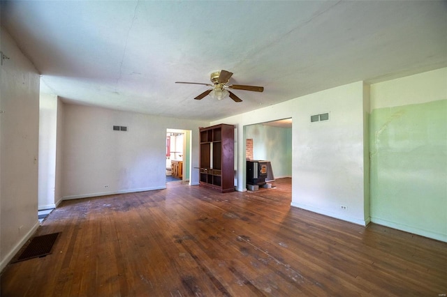 unfurnished room with a wood stove, visible vents, and dark wood-style flooring