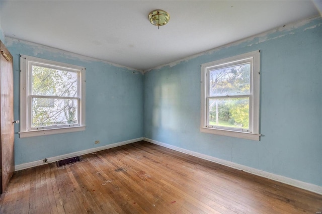 spare room with visible vents, baseboards, and hardwood / wood-style floors