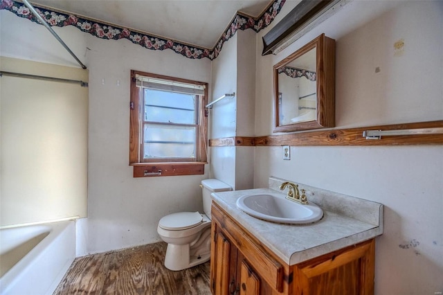 full bathroom featuring a washtub, vanity, toilet, and wood finished floors