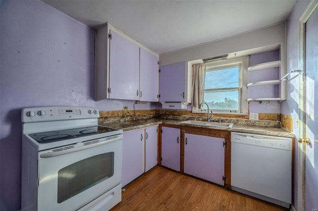 kitchen with dark countertops, white appliances, light wood-style flooring, and a sink