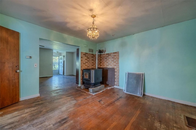 unfurnished living room featuring a wood stove, visible vents, baseboards, and hardwood / wood-style floors