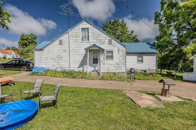 rear view of house with metal roof and a yard