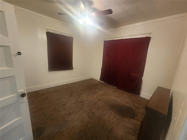 spare room featuring dark colored carpet and ceiling fan