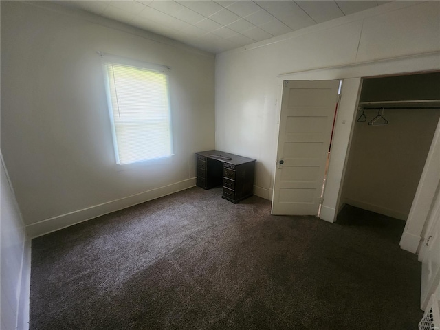 unfurnished bedroom featuring dark carpet and a closet