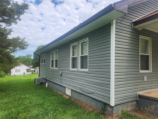 view of side of home featuring cooling unit and a yard