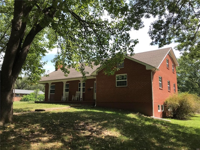 rear view of house with brick siding and a yard