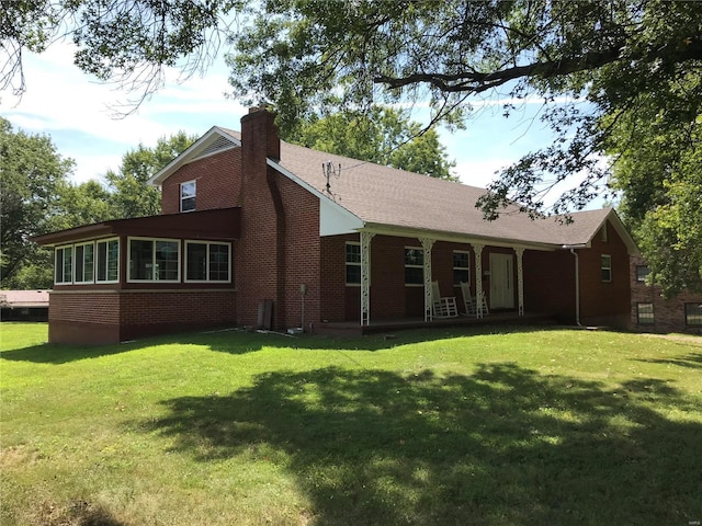 back of house featuring a shingled roof, brick siding, a yard, and a chimney