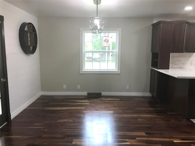 unfurnished dining area featuring dark wood finished floors, visible vents, and baseboards