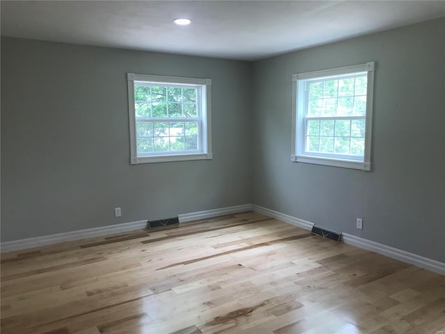 unfurnished room with recessed lighting, baseboards, visible vents, and light wood finished floors