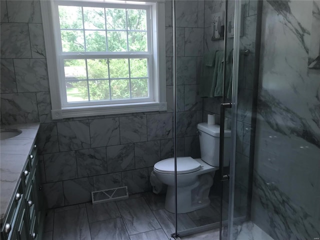 bathroom with vanity, a shower stall, visible vents, and tile walls