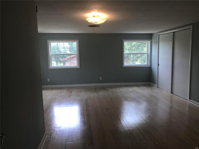 unfurnished bedroom with a closet, baseboards, and wood finished floors