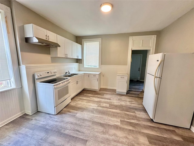 kitchen with a healthy amount of sunlight, white cabinetry, light hardwood / wood-style floors, and white appliances