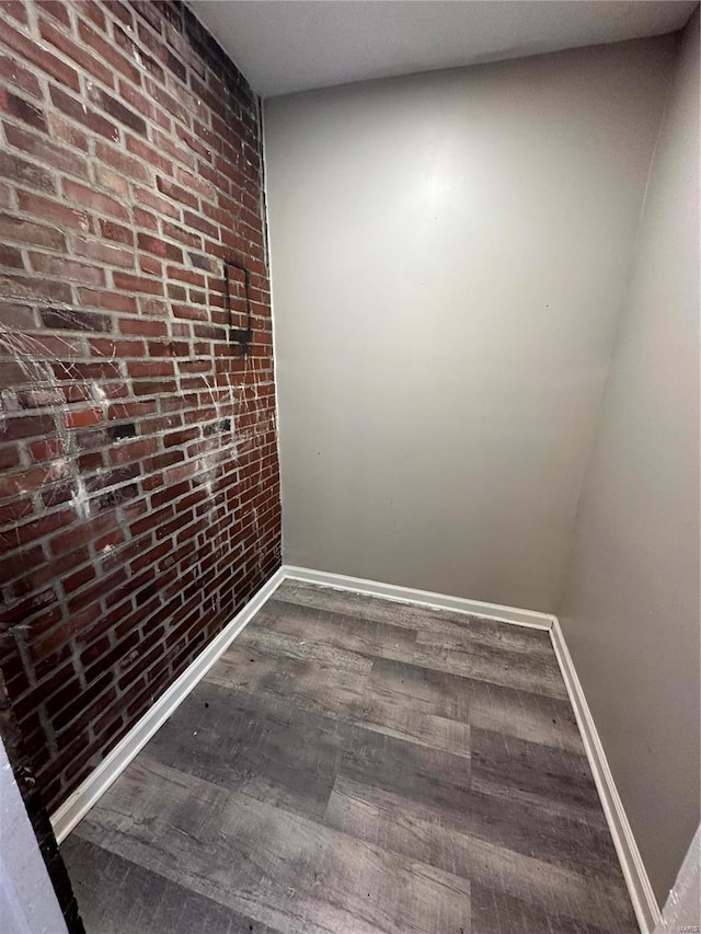 spare room featuring hardwood / wood-style floors and brick wall