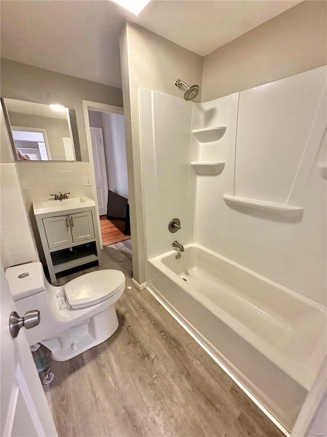 full bathroom featuring hardwood / wood-style flooring, vanity,  shower combination, and toilet