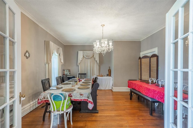 dining space with a chandelier, wood-type flooring, and a textured ceiling