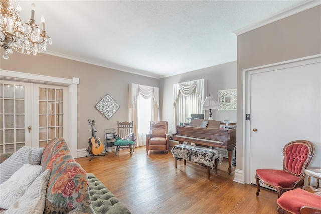 living room with french doors, ornamental molding, a notable chandelier, and wood-type flooring