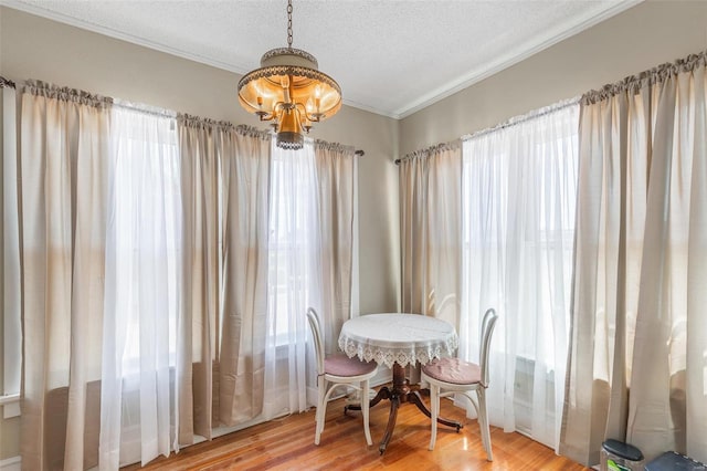 dining space with hardwood / wood-style flooring, crown molding, a textured ceiling, and an inviting chandelier