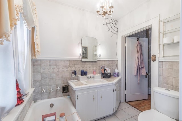 bathroom with tile patterned floors, a bathtub, vanity, a notable chandelier, and toilet