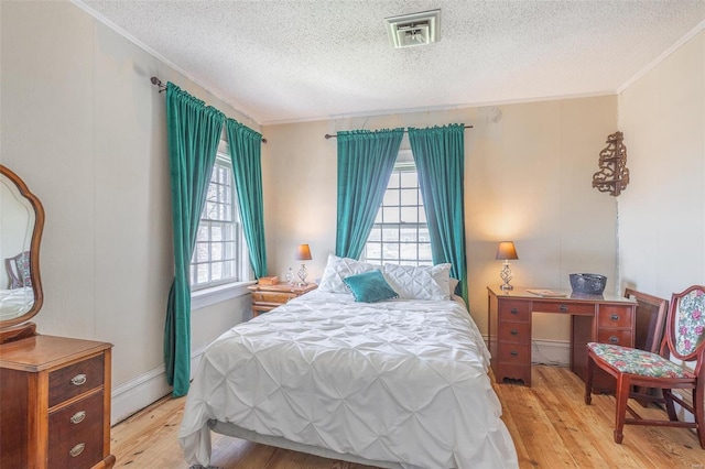 bedroom featuring a textured ceiling, light wood-type flooring, and ornamental molding