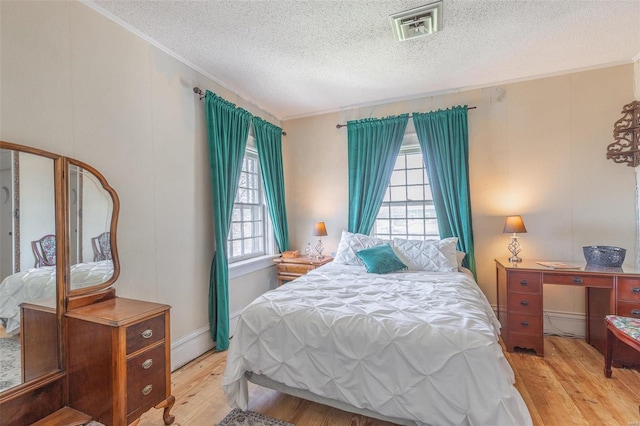 bedroom with a textured ceiling, a baseboard radiator, and light hardwood / wood-style flooring