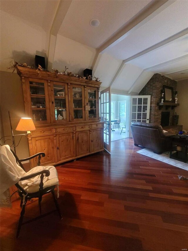 living area with brick wall, lofted ceiling, and dark hardwood / wood-style flooring