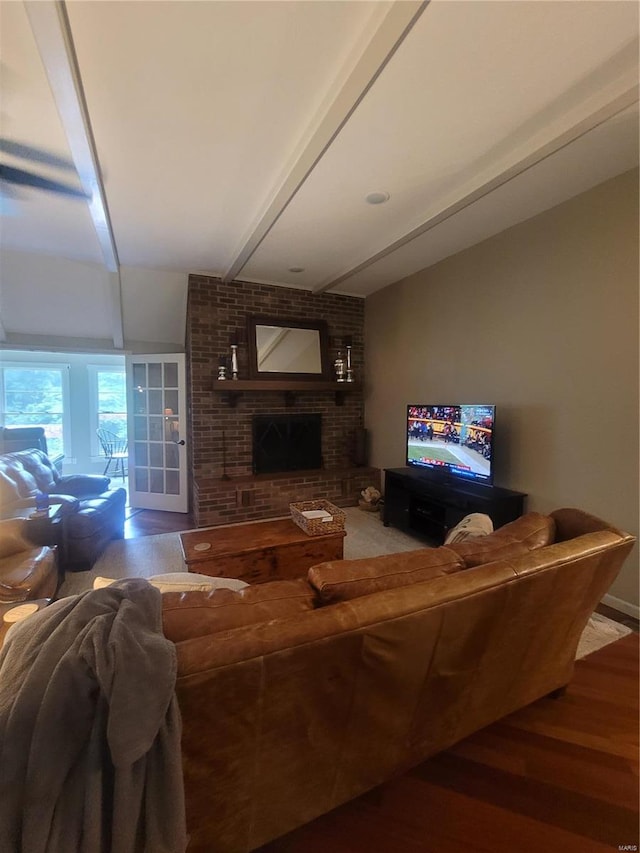 living room with hardwood / wood-style floors, a fireplace, beam ceiling, and brick wall