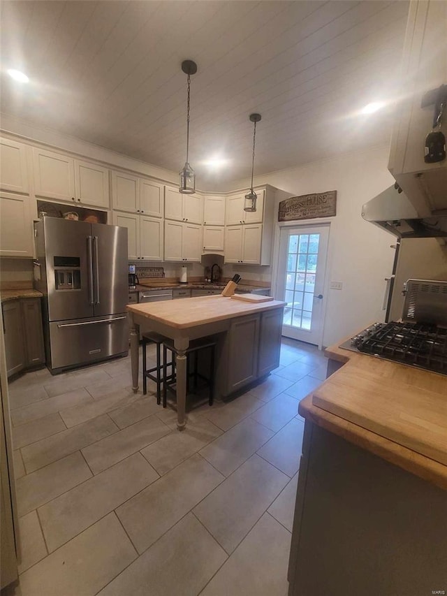 kitchen featuring fume extractor, an island with sink, light tile flooring, stainless steel refrigerator with ice dispenser, and hanging light fixtures