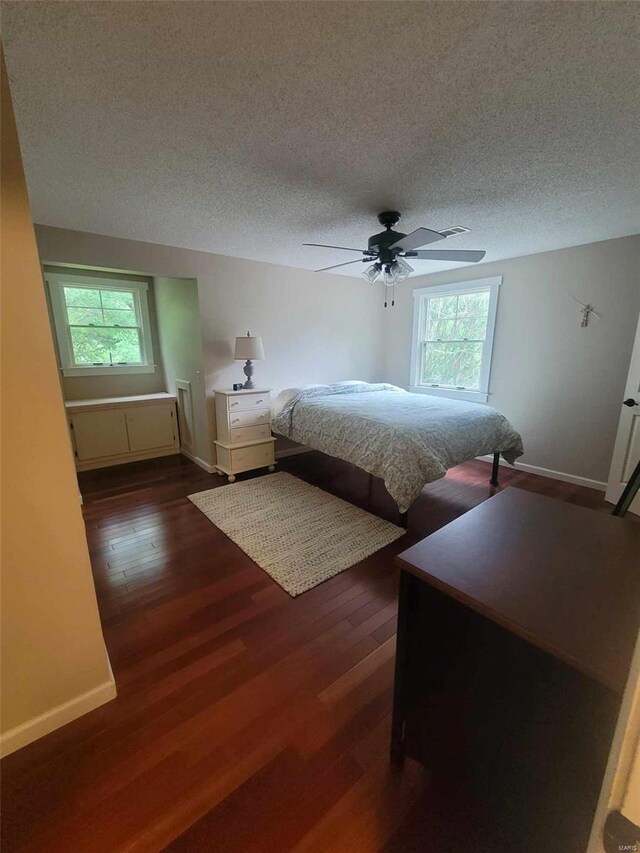 bedroom with dark hardwood / wood-style floors, ceiling fan, multiple windows, and a textured ceiling