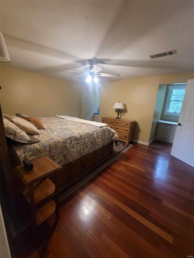 bedroom featuring ceiling fan, a textured ceiling, and dark wood-type flooring