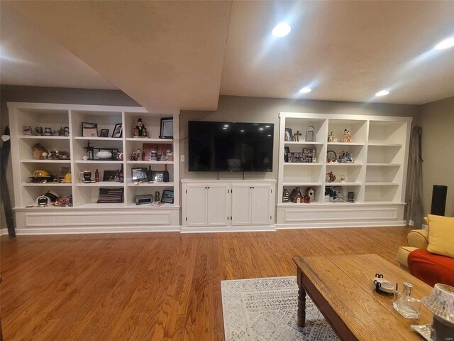 unfurnished living room featuring built in features and light wood-type flooring