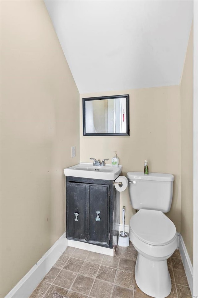 bathroom with toilet, vanity, and vaulted ceiling