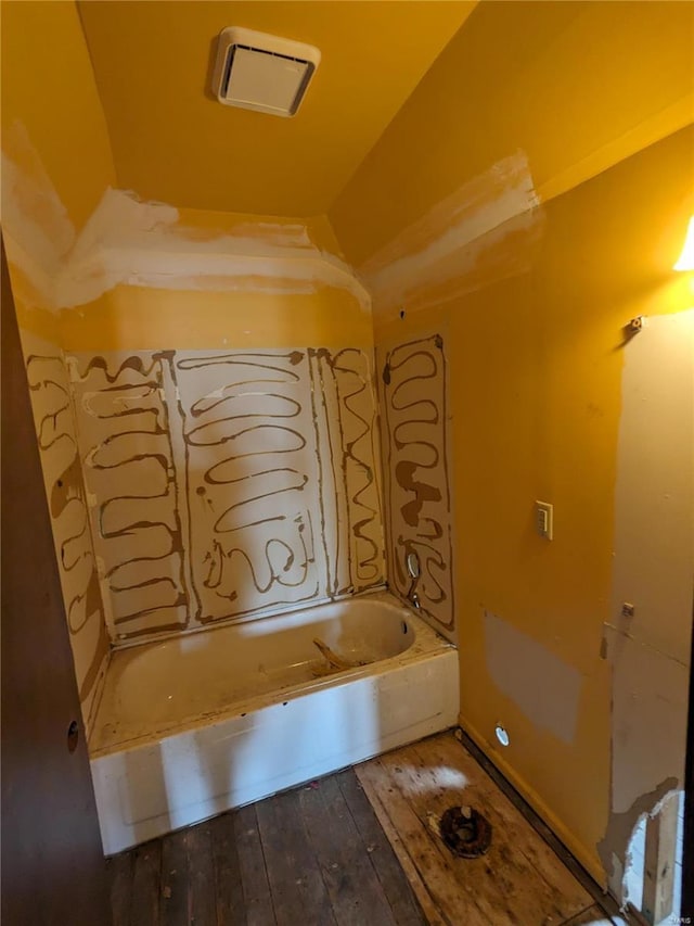 bathroom featuring hardwood / wood-style floors, lofted ceiling, and a bathing tub