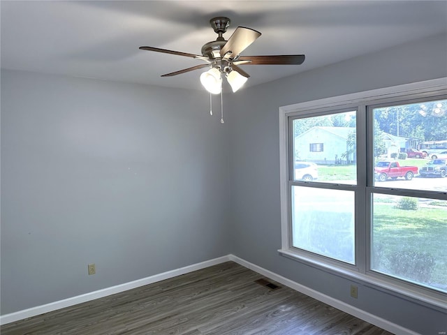 empty room with dark hardwood / wood-style floors, plenty of natural light, and ceiling fan