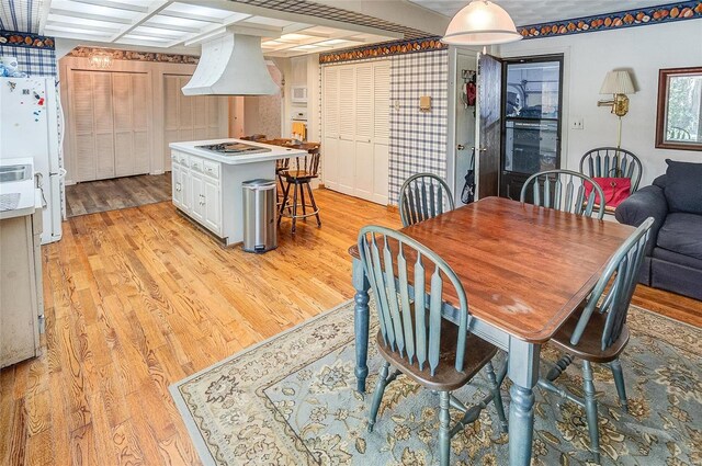 dining room with coffered ceiling and light hardwood / wood-style flooring