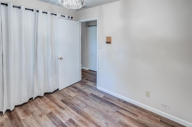 empty room with a notable chandelier, hardwood / wood-style flooring, and a textured ceiling