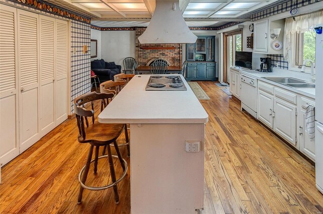 kitchen featuring coffered ceiling, a fireplace, light wood-type flooring, and a kitchen bar