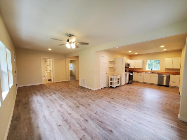 unfurnished living room featuring sink, light wood-type flooring, and ceiling fan